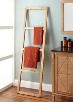 a wooden towel rack in a bathroom next to a mirror