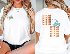 a woman wearing a miami dolphins t - shirt with the word miami on her chest