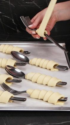 a person holding a knife and fork over some uncooked pasta on a pan