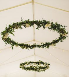 wedding decorations hanging from the ceiling in a marquee with white flowers and greenery