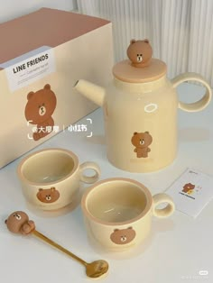 a tea set with two mugs and a teddy bear on the front is sitting next to a box