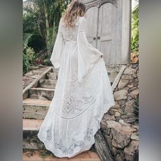 a woman in a white dress is walking up some steps and looking at the door