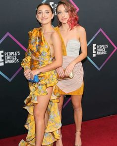 two women standing next to each other on a red carpet with people's choice awards in the background