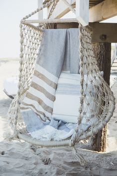 towels are hanging in a hammock on the beach