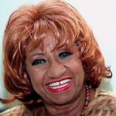 a close up of a person wearing a necklace and smiling at the camera with red hair