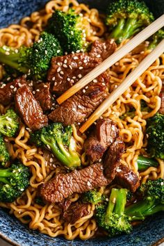 beef and broccoli stir fry in a blue bowl with chopsticks on top