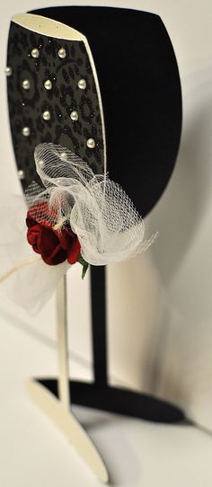 a black and white hat with a red rose in it's centerpiece on a stand