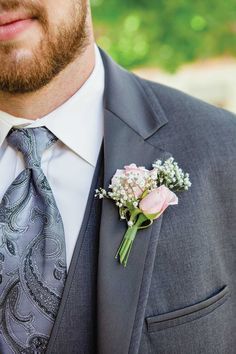 a man wearing a suit and tie with a boutonniere on his lapel