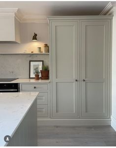 a kitchen with white cabinets and marble counter tops