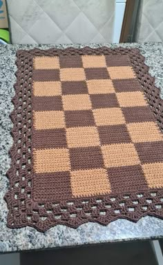 a crocheted table top with a brown and tan checkerboard pattern on it