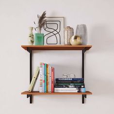 two wooden shelves with books, vases and other decorative items on them against a white wall