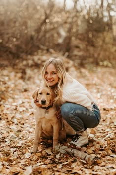 a woman kneeling down with her dog in the leaves