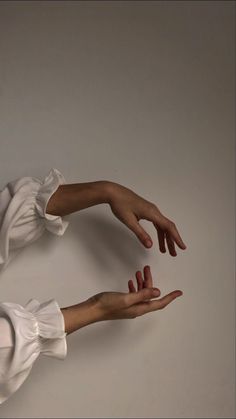 two hands reaching out towards each other with their fingers extended in the air, against a gray background