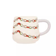 a white mug with a red and green chain on the front, sitting on a white surface