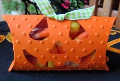 an orange pumpkin shaped box with candy inside