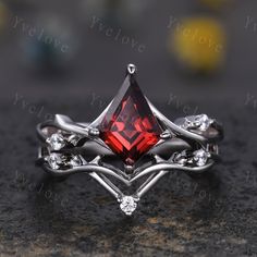 a close up view of a ring with a red stone in the center and white diamonds around it