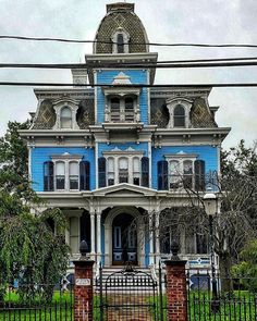 a large blue house with white trim on the front and side of it's windows