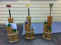 three wooden posts holding golf balls and tees on top of a cement ground next to a house