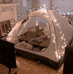 a tent that has been set up in the living room with christmas lights on it