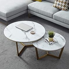 two white marble coffee tables sitting on top of a gray carpeted floor next to a couch