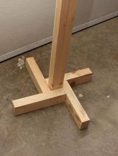 a wooden cross on the ground in front of a white wall and floor with cement