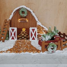 a christmas scene made out of cookies and other holiday treats on a table with a barn in the background