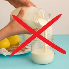 a person pouring milk into a glass jar with lemons in front of it on a plate