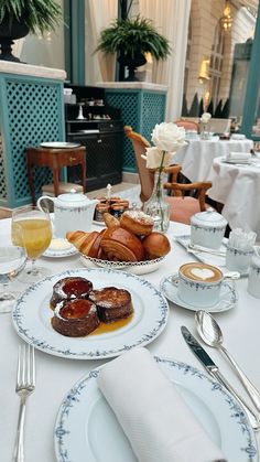 the table is set with two plates of pastries, coffee and orange juices