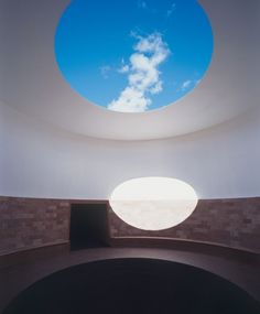 an empty room with a skylight in the center and a round window on the wall