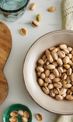 a bowl filled with nuts next to a cutting board