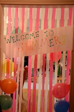 a welcome sign hanging from the side of a door decorated with balloons and streamers