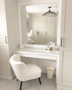 a white chair sitting in front of a vanity with a mirror on top of it