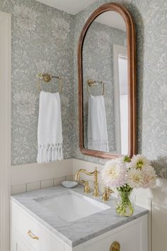 a white sink sitting under a bathroom mirror next to a wooden framed mirror on a wall