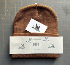 a brown beanie with a sticker on it sitting on top of a piece of paper