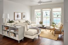 a living room filled with furniture and windows next to a wooden floor covered in hard wood floors