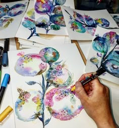 someone is painting flowers on paper with watercolors