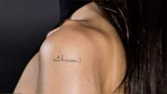 the back of a woman's shoulder with arabic writing on it