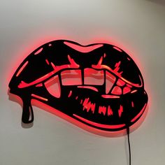 a lit up neon sign that has a mouth and tongue on it's side