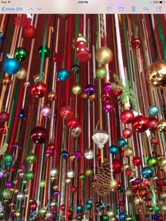 a room filled with lots of colorful christmas ornaments hanging from the ceiling and lights on the ceiling