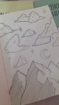 a drawing of mountains and clouds with stars in the sky above them on top of a book