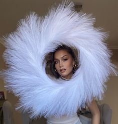 a woman with white feathers on her head is posing in front of a mannequin