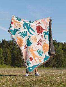 a woman is holding up a blanket in the grass