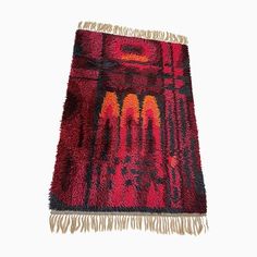 a red and black rug with fringes on the bottom, in front of a white background