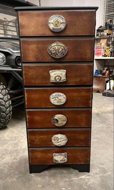 a wooden dresser with metal knobs on it's drawers in a garage next to a car