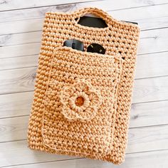 a crocheted purse sitting on top of a white wooden floor next to a cell phone