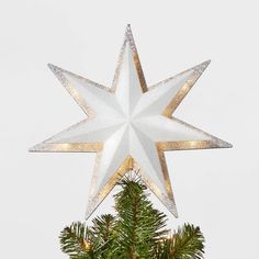 a white star hanging from the top of a christmas tree