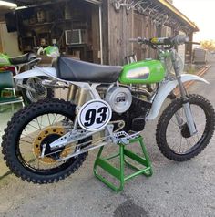 a green and white dirt bike parked in front of a building