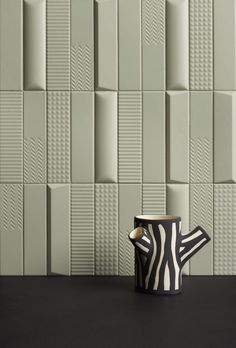 a black and white coffee cup sitting on top of a table next to a wall