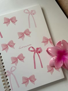 a notepad with pink bows and a flower on the cover, next to a spiral notebook