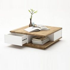 a wooden table with a book on it and a potted plant in the middle